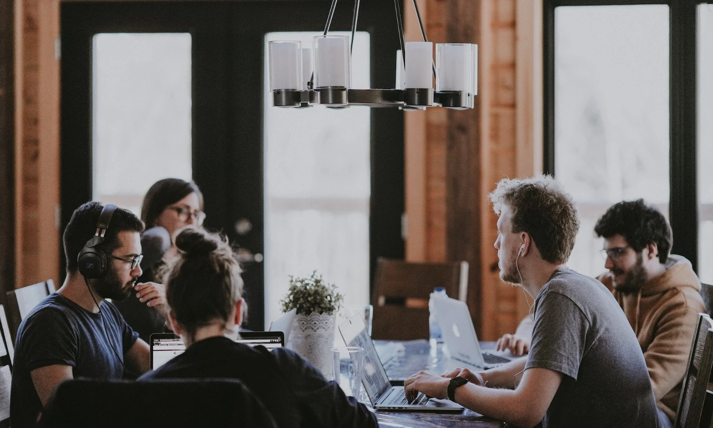 people sitting around a table working and having a meeting. Photo by annie spratt via unsplash